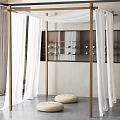 Wooden Four Poster Structure With White Sheer Curtains And Round Woven Cushions