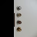 Various Metal Door Knobs in Different Tones on Light Gray Door Panel