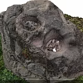 Natural Rock Decorative Structure With Cavities And Green Plants On Grass Base