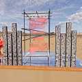 Outdoor Art Installation With Metal Frame Red Elements And Vertical Panels On Sandy Ground