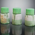 Three Glass Bottles With Green Caps And Stained Labels On Black Reflective Surface