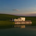 White Detached Villa Lakeside With Green Grass Trees Sunset Sky And Lake Reflection