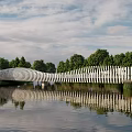 Scenic Wavy White Landscape Bridge Over Water With Reflection And Green Trees
