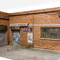 Building Exterior Wall With Brick Structure Graffiti Roll Up Doors And Barred Windows