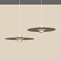 Two Pendant Lights Featuring Circular Light Brown Shades And White Bodies Against Light Colored Wall