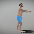 Shirtless Man in Blue Shorts Standing with Arms Stretched Forward Against Gray Background
