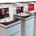 Transparent Display Shelf Showcasing Headphones With Screen Portraits And Swiss Price Information