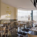 Modern Restaurant Interior With Wooden Dining Tables Chairs Pendant Lights And Large Windows