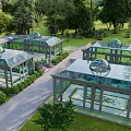 Glass Greenhouses with Dome Roofs in Lush Garden Landscape Surrounded by Trees and Pathways