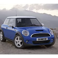 Blue Mini Cooper Two Door Car With White Roof And Silver Wheels In Mountain Landscape