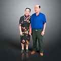 A Man In Blue Shirt Standing With Woman In Floral Dark Dress Against Gray Background