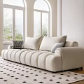 Beige Three-Seater Sofa With Plush Rounded Cushions White Walls Windows And Round Coffee Table