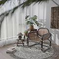 Comfortable Rattan Leisure Chair in Sunlit Corner with Woven Rug Potted Plants and Wooden Art