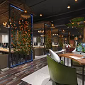 Modern Internet Cafe With Wooden Elements Green Plants Computers Comfortable Tables Chairs and Warm Lighting