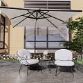 Comfortable Outdoor Sofa with Umbrella and Two Chairs on Stone Patio with Green Plants