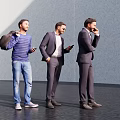 Three Men Standing Together in Modern Urban Setting Using Phones and Carrying Bags