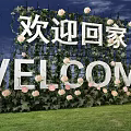 Welcome Home Sign Decorated With Green Plants And Pink Flowers