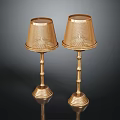 Two Gold Table Lamps With Mesh Shades Bamboo Poles And Textured Bases On Black Background