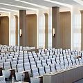 Modern Conference Room With Rows Of Seats Ceiling Lights And Wooden Panel Background
