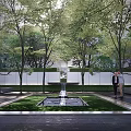Serene Residential Landscape With Lush Trees Green Lawn Central Fountain And White Walls
