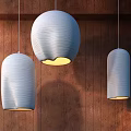 Three Light Blue Wavy Texture Pendant Lights Illuminated On Wooden Wall With Warm Glow
