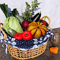 Fresh Assorted Vegetables in Wicker Basket with Blue and White Patterned Cloth on Gray Countertop