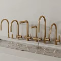 Different Styles Brushed Gold Faucets On White Countertop With Flowing Water