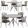 Round Outdoor Table With Metal Legs And Woven Rattan Chairs Red Black Cushions