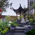 Chinese Garden Landscape Featuring Pagoda Waterfall Stone Bridge Lush Greenery and High-rise Buildings