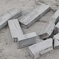 Broken Concrete Blocks Scattered On Ground With Cracks And Metal Fasteners