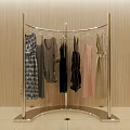 Curved Silver Metal Clothes Rack Displaying Dresses Tops and Garments with Beige Wall Background