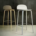 Two Modern Bar Stools With Wooden And Metal Frames Against Dark Wall And Light Floor