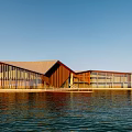 Modern Waterfront Building With Wooden Structure Glass Facade Sloped Roof And Blue Sky