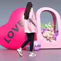 Woman In Pink Coat Near Large LOVE Heart Flower Arch And LOVE Ball