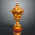 Elegant Golden Trophy With Ornate Carvings Lid Handles And Red Base Design