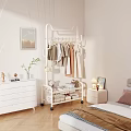 Stylish Hanging Clothes On White Rolling Rack In Cozy Bedroom With Dresser And Plant