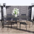 Outdoor Table Set with Black Chairs White Vase and White Flowers on Wooden Deck
