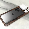 Silver iPhone With Multiple Cameras And White AirPods On Wooden Tray Over Marble Surface