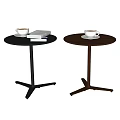 Two Modern Circular Side Tables With Black Legs Holding Coffee Cups And Books