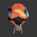 A man holding a cat in orange T-shirt and blue shorts against black background
