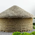 Courtyard Garden With Round Thatched Roof Building Earthen Wall Stones Green Shrubs And Pine Tree