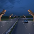 Curved Arch Shaped Landscape Sculptures Along Highway Illuminated At Night With Cars Driving