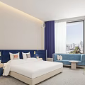 Hotel Guest Room With City View Blue Sofa Red Chair Round Mirror And Vanity