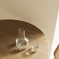 Clear Glass Cup And Carafe On Wooden Round Table With Light Colored Wall And Sunlight