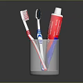 Essential Daily Household Essentials With Two Toothbrushes And Toothpaste Tube In Transparent Glass Cup