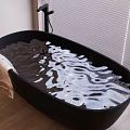 Black Oval Bathtub With Rose Petals And Towel On Wooden Floor Near Window Blinds