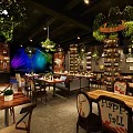 Modern Restaurant Interior With Green Plants Dining Tables Chairs Hanging Lights And Live Music