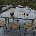 Outdoor Table with Rattan Chairs Vase Drinks and Lemon Slices on Wooden Deck by Water