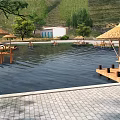 Scenic Hillside Pool Area With Wooden Platforms Thatched Umbrellas And Lounge Chairs