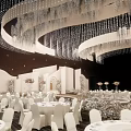 Elegant Banquet Hall Interior With White Arches Crystal Chandeliers And White Tables